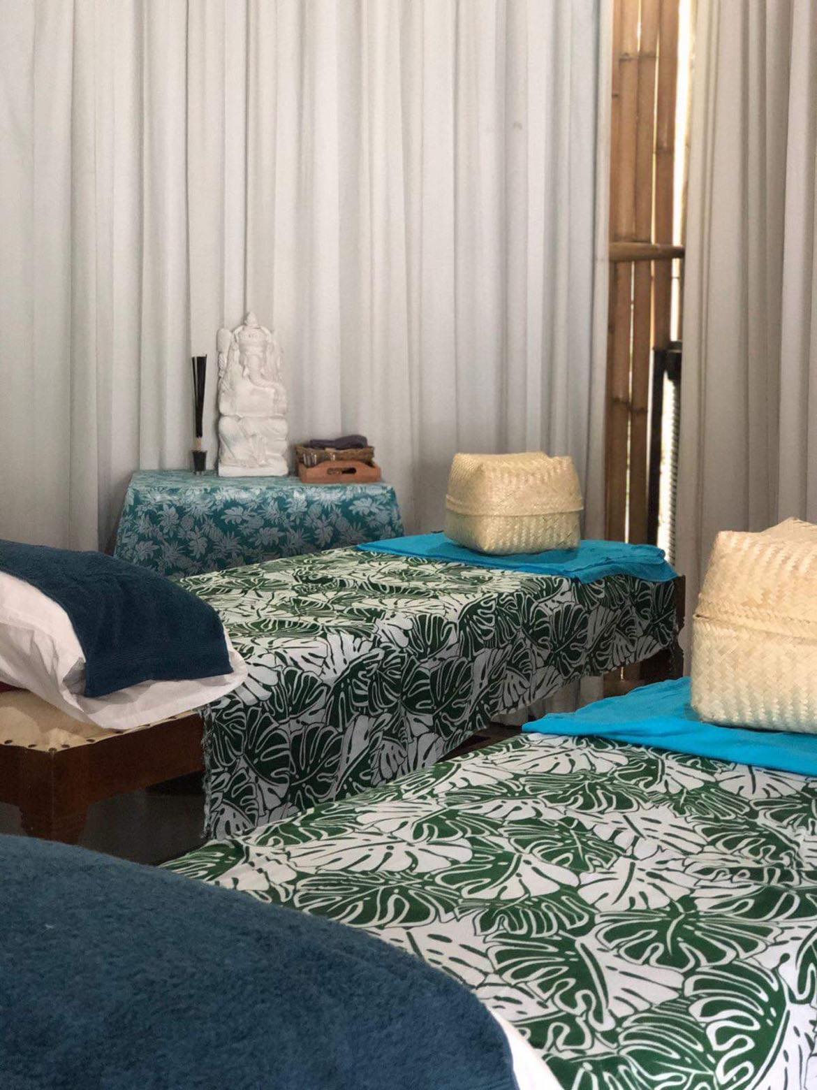 SALT Bali Spa treatment room with two massage beds, tropical leaf-patterned covers and traditional Balinese décor.