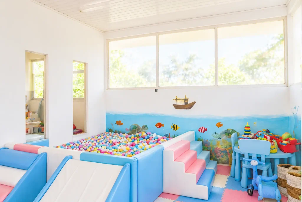 Bright indoor playroom with padded flooring, toys and natural light at Salty Monkeys Kids Club in Amed